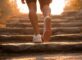 Person taking a small step up a staircase with a sunrise in the background